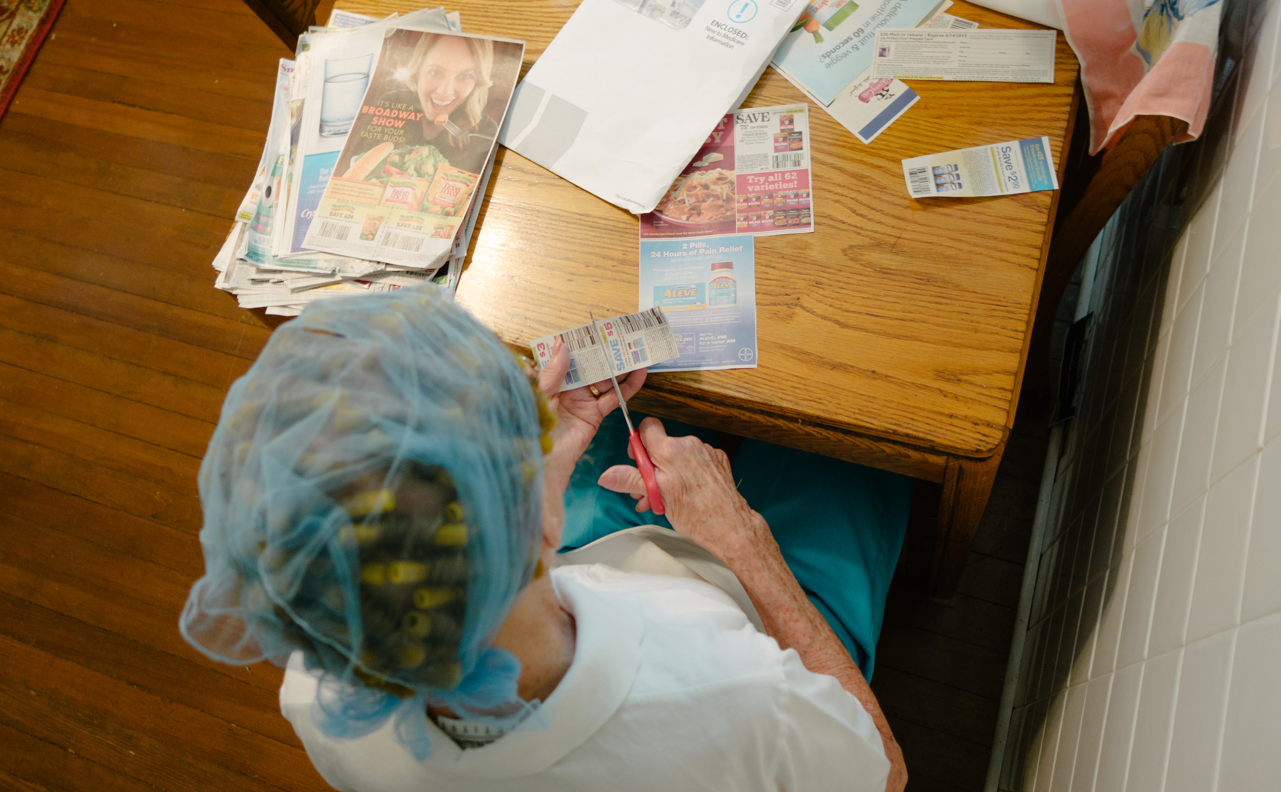 Grandma at the kitchen table, clipping coupons on a Saturday night