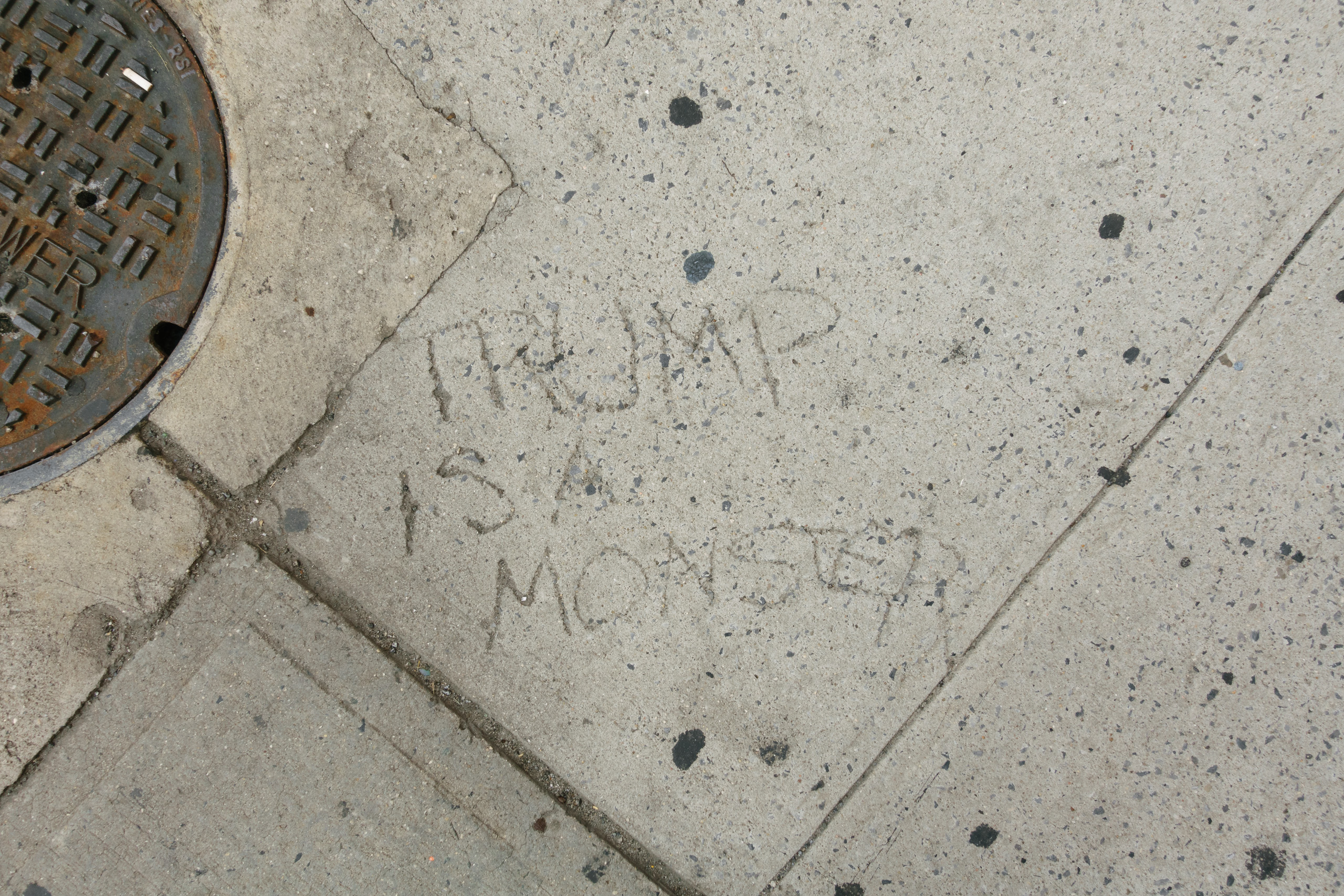 TRUMP IS A MONSTER says the sidewalk on Spring Street at 7th Avenue