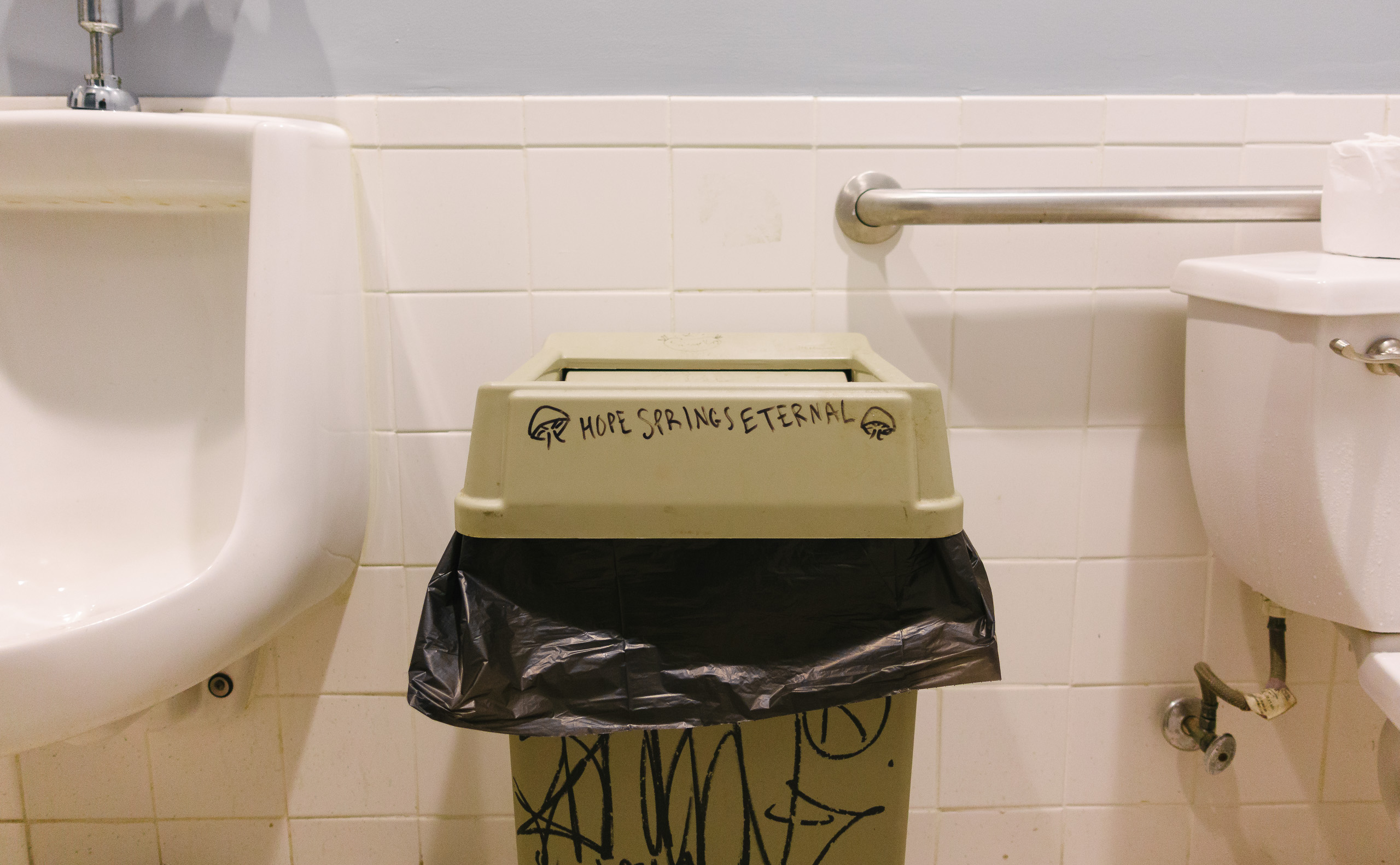 A trash bin in a men's room