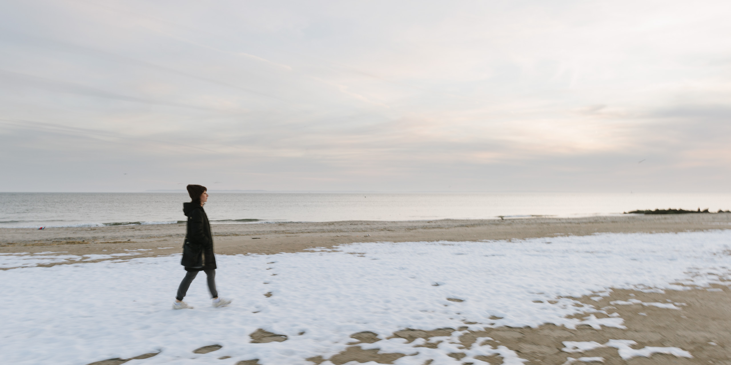 woman walking snow-covered coney island beach