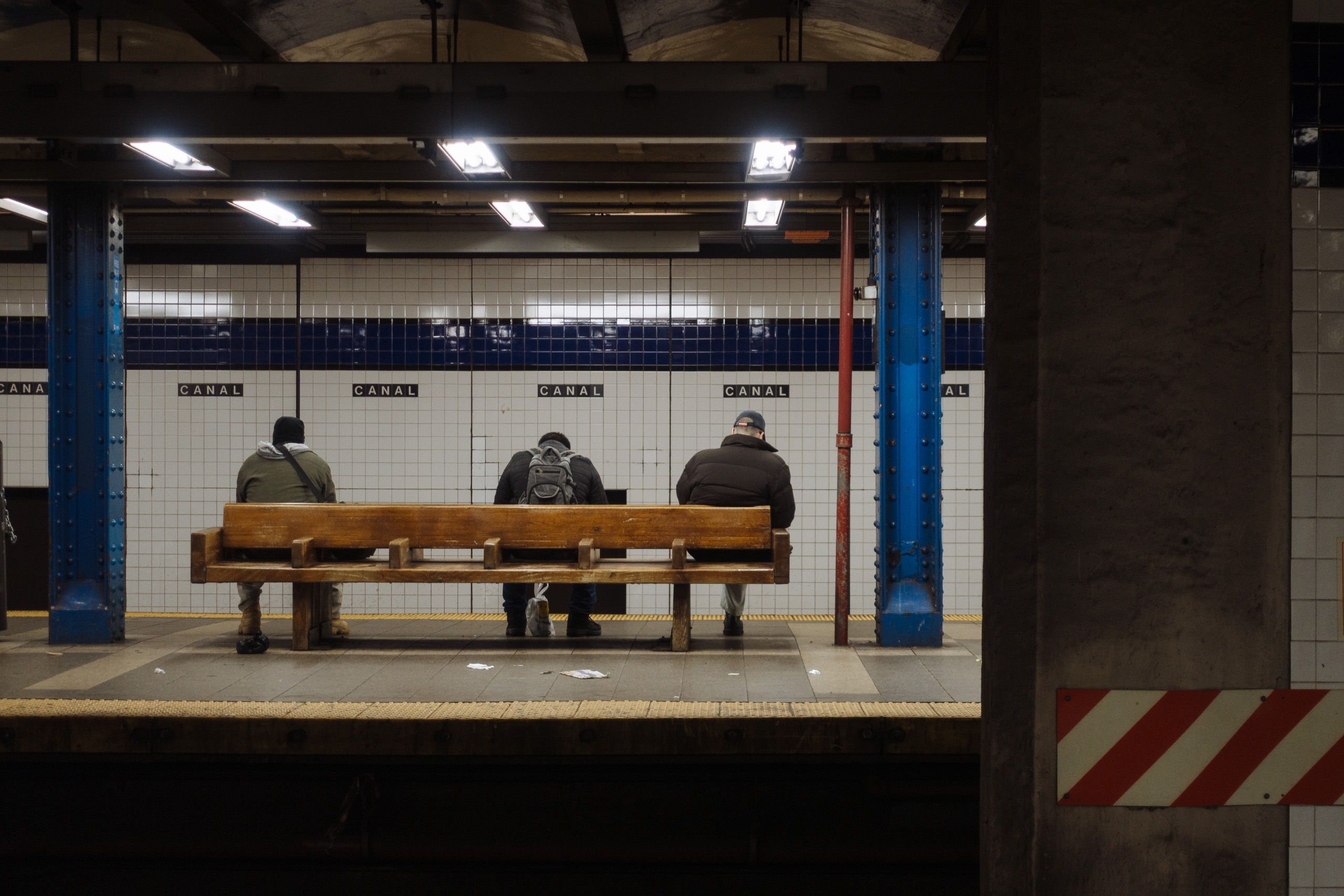 Men on a bench waiting for the train at Canal Street