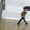 A man under an umbrella dashes past a barber shop Houston Street