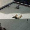 A worker rests on a rooftop in the sun passing between two highrises