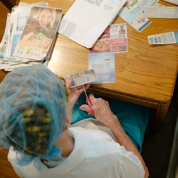 Grandma at the kitchen table, clipping coupons on a Saturday night