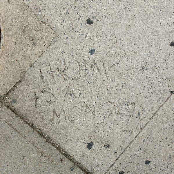 TRUMP IS A MONSTER says the sidewalk on Spring Street at 7th Avenue