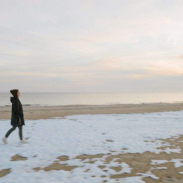 woman walking snow-covered coney island beach