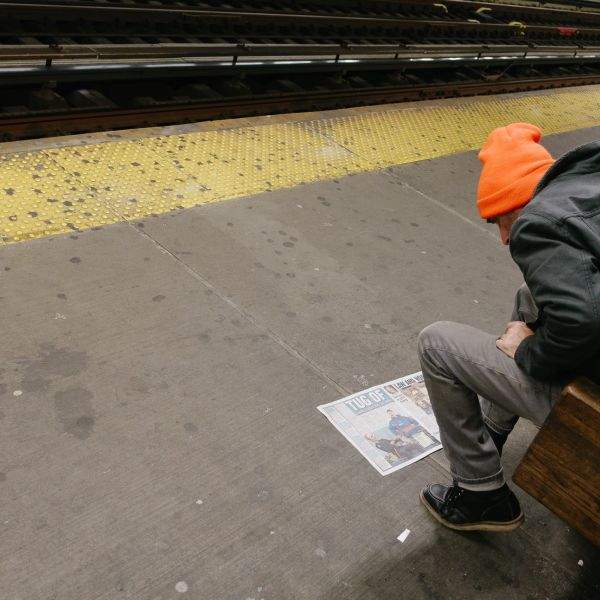 Man reading NY Daily News or something on the subway platform