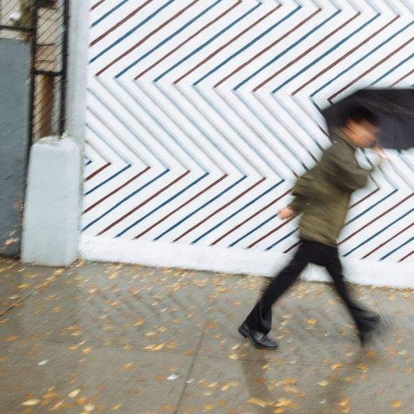 A man under an umbrella dashes past a barber shop Houston Street