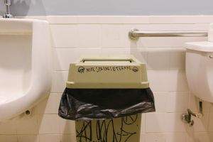 A trash bin in a men's room