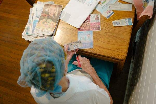 Grandma at the kitchen table, clipping coupons on a Saturday night