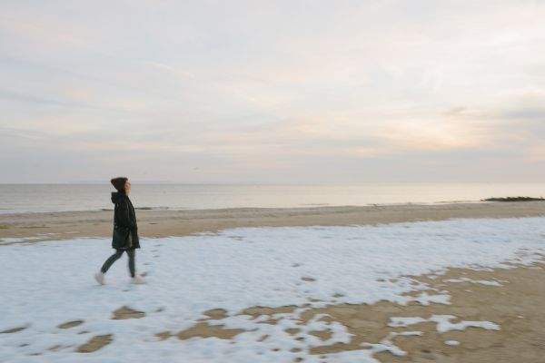 woman walking snow-covered coney island beach