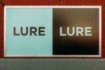 A street level &quot;Lure&quot; sign on a wall in Hudson Square