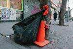 Garbage bag attached to a small, gloved traffic cone.