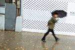 A man under an umbrella dashes past a barber shop Houston Street