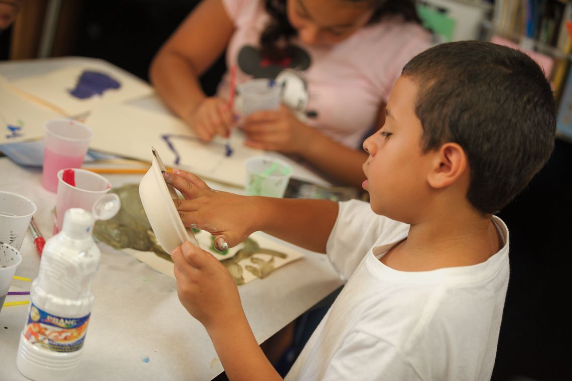 student dipping fingers in paint