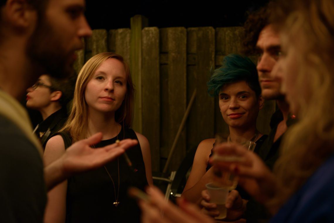 Guests chat and mingle and stare directly into the camera