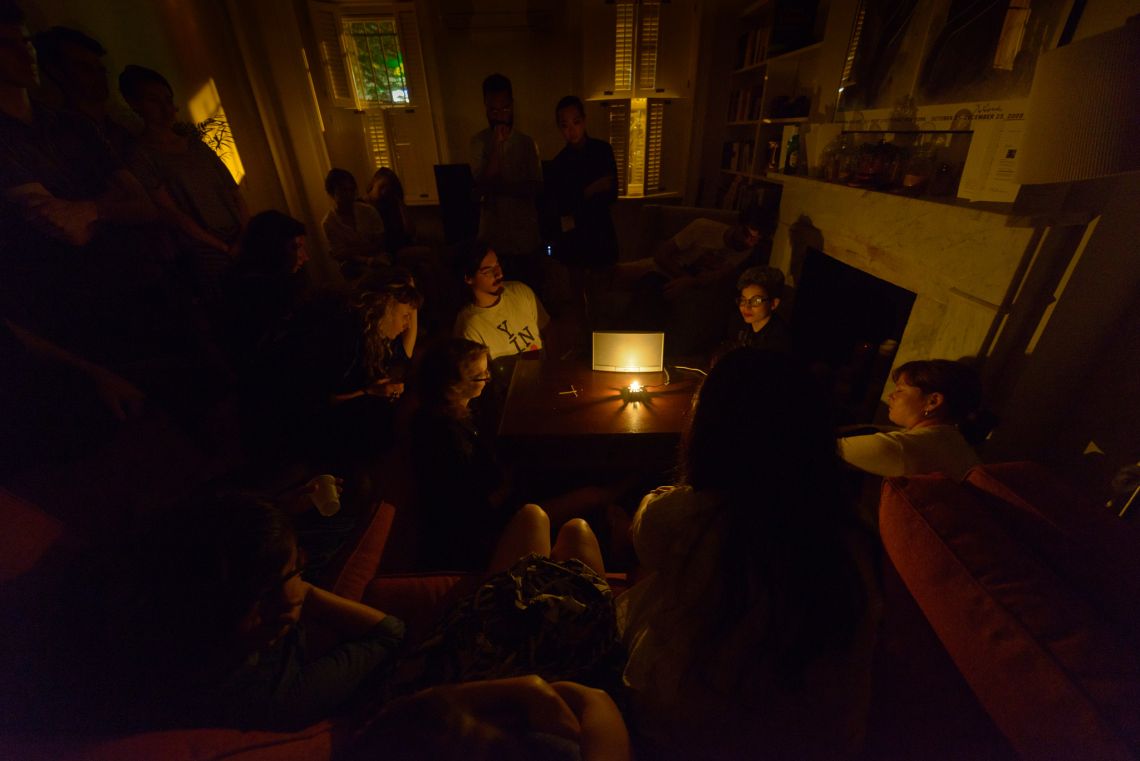 Guests gather around to listen to the the audio produced by circuits and sensors reacting to light produced by the burning candle
