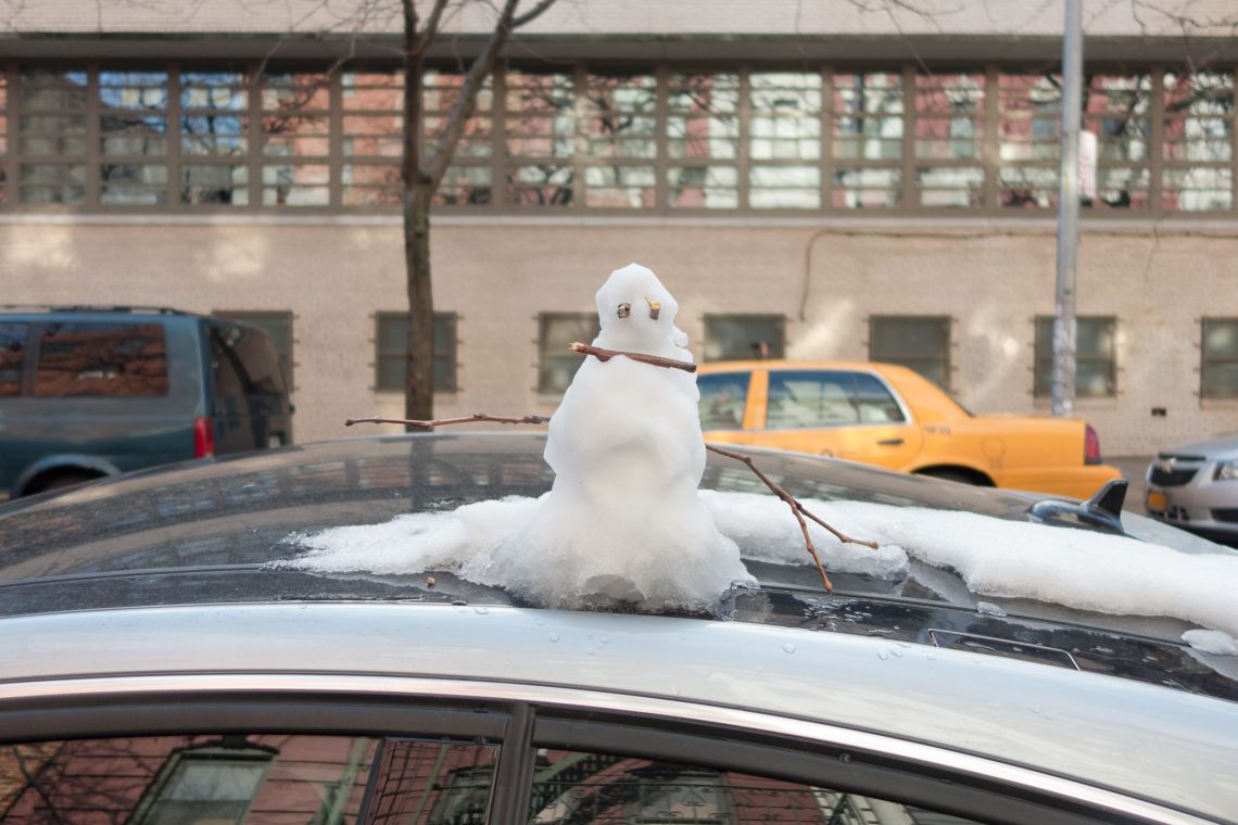 Tiny snowman on top of a car
