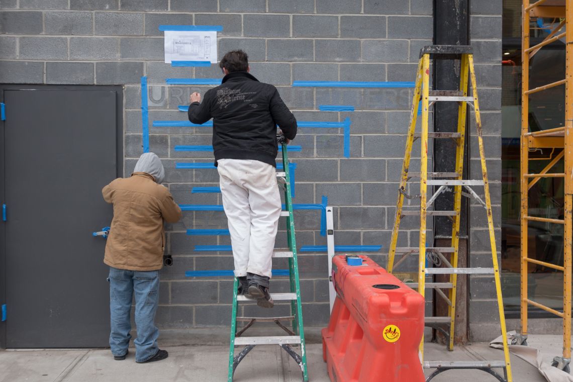Laborers prep the wall for the Urban Outfitters signage in Williamsburg