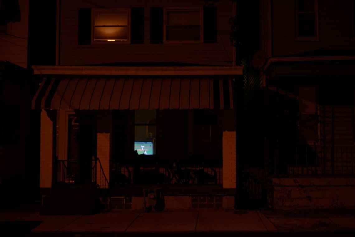 Residents watch a baseball game in their living room