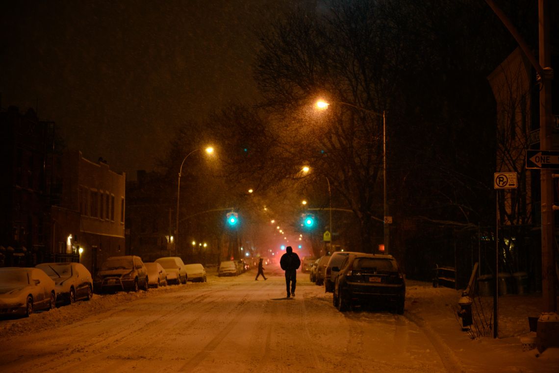 People walk in the street at the intersection outside my apartment.