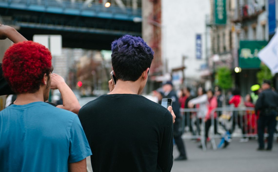 Young men documenting the May Day March long 2nd Avenue