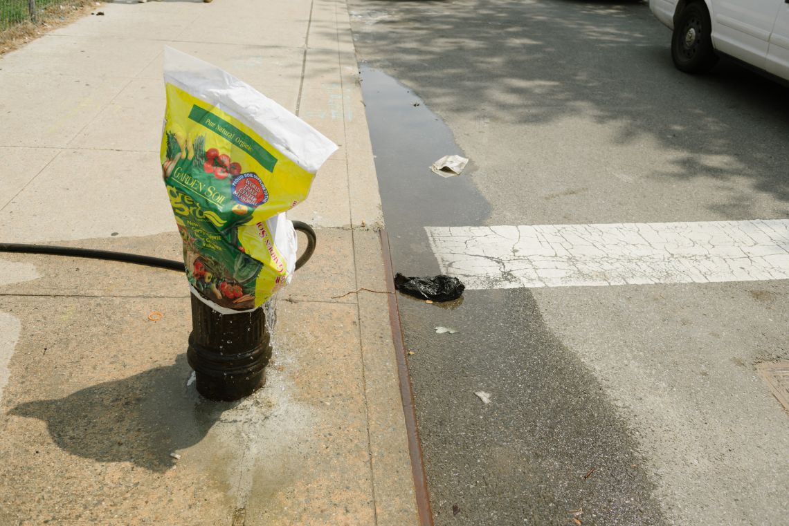 The leaking fire hydrant is covered with an empty plastic bag
