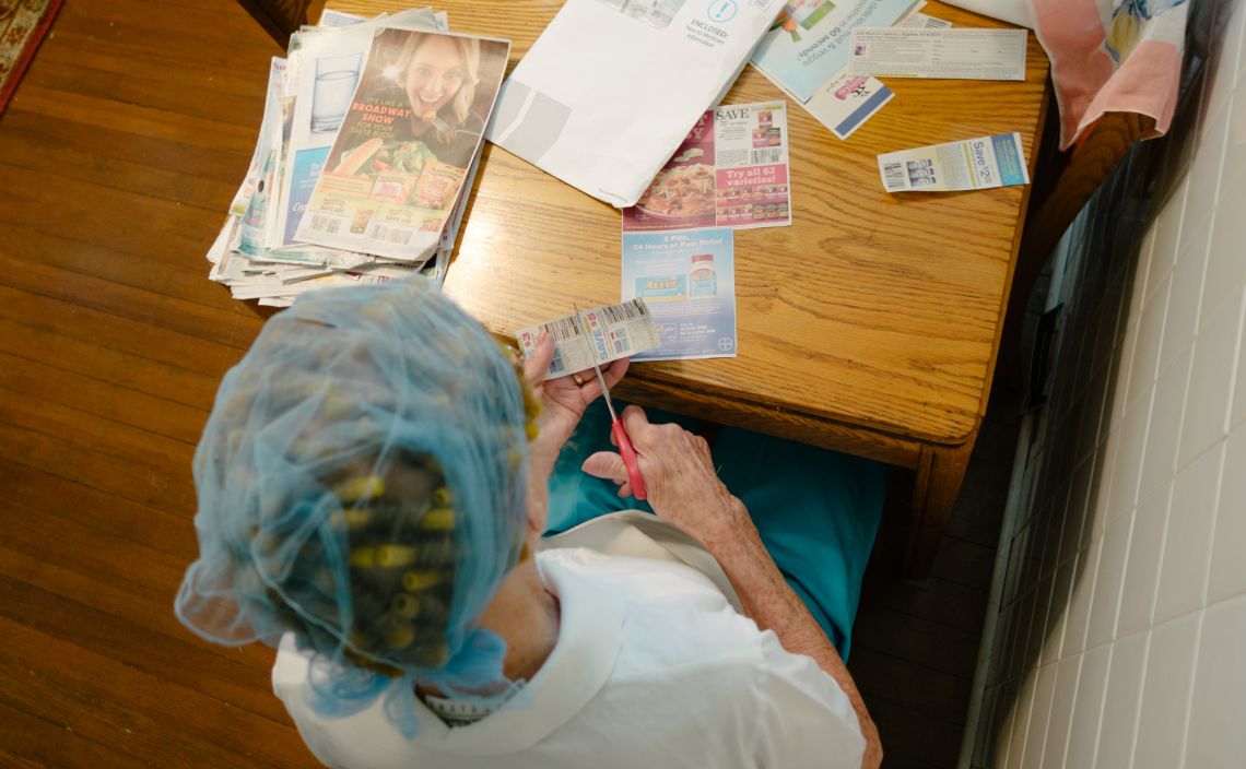Grandma at the kitchen table, clipping coupons on a Saturday night