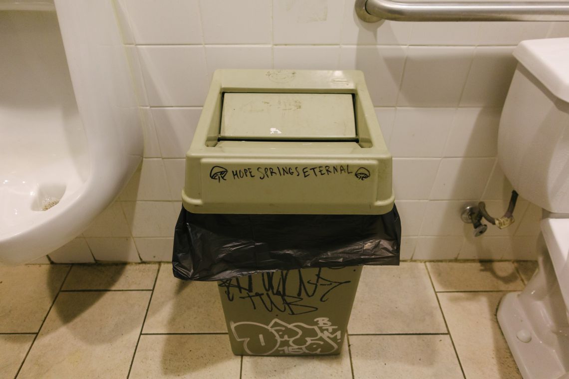 A trash bin in a men's room