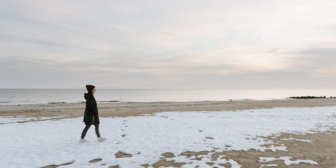 woman walking snow-covered coney island beach