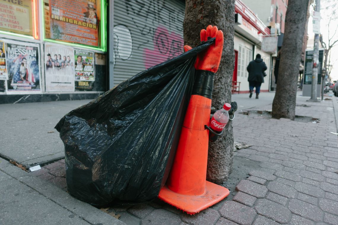 Garbage bag attached to a small, gloved traffic cone.