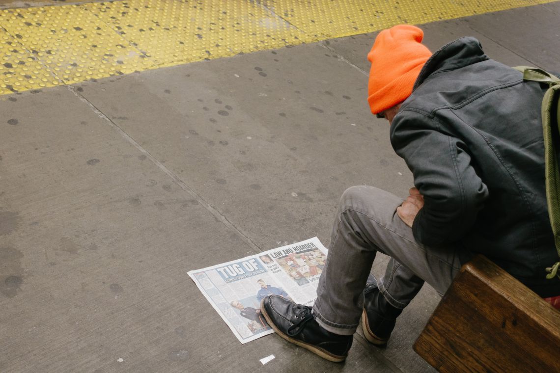 Man reading NY Daily News or something on the subway platform
