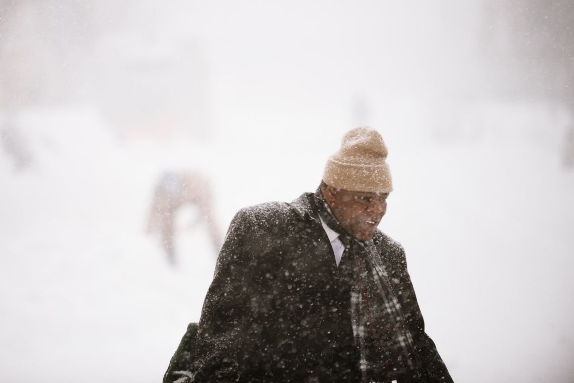 Commuter from Kosciusko St stop, walking past snow removal laborer, Lexington Ave