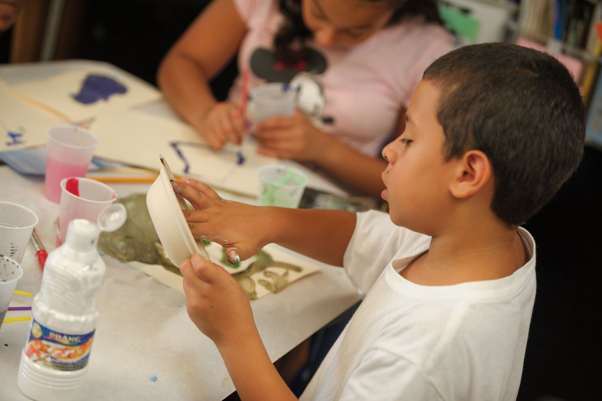 student dipping fingers in paint