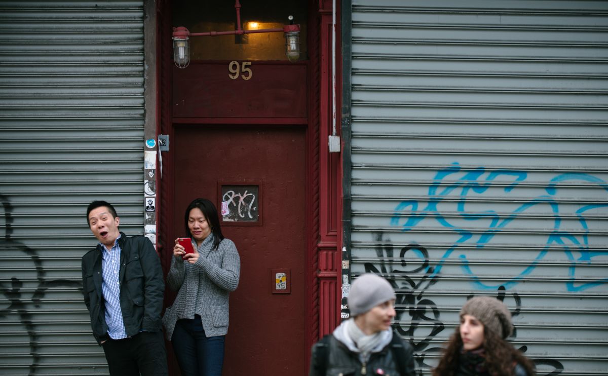 Man and woman, who was trying to hide behind him, documenting the May Day March long 2nd Avenue