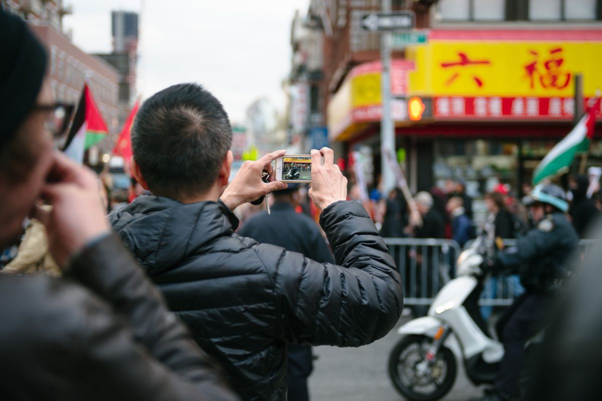 Man documenting the May Day March long 2nd Avenue