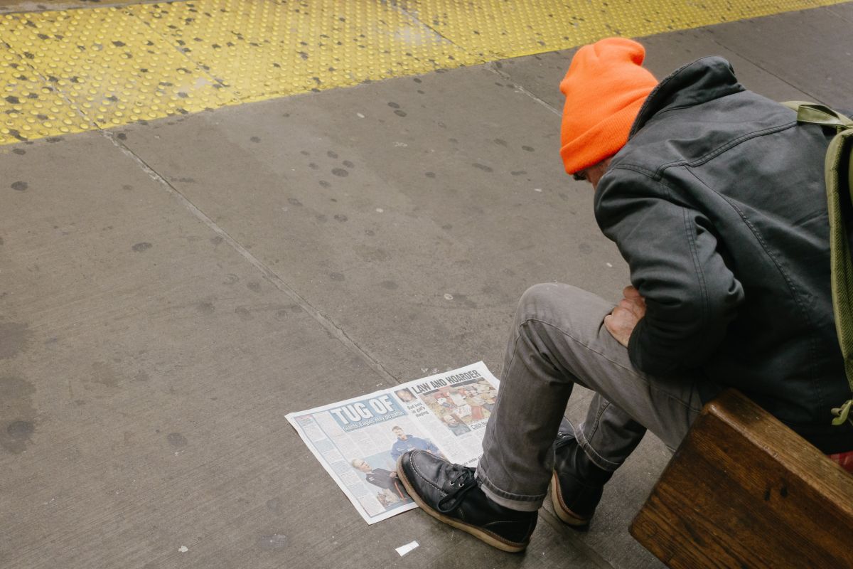 Man reading NY Daily News or something on the subway platform