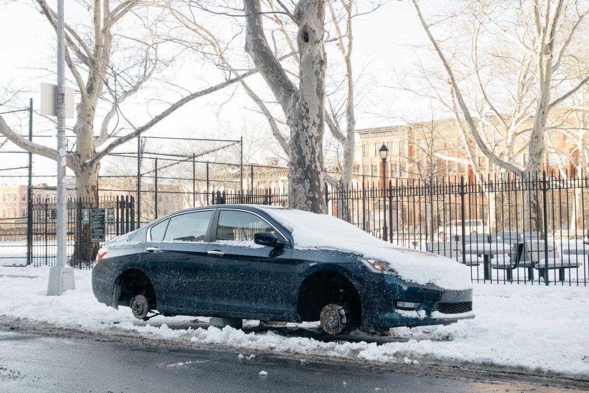 A car on cinder blocks outside a playground in Bed-Stuy