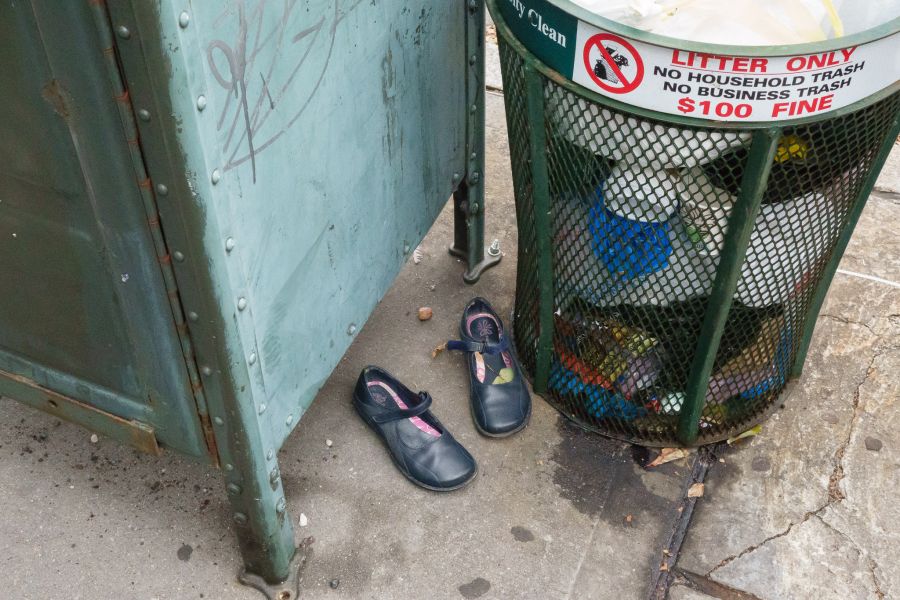 Shoes by a garbage can