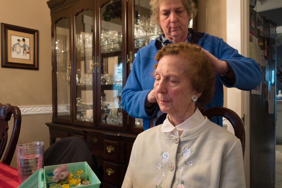 woman helping mother put hair in rollers