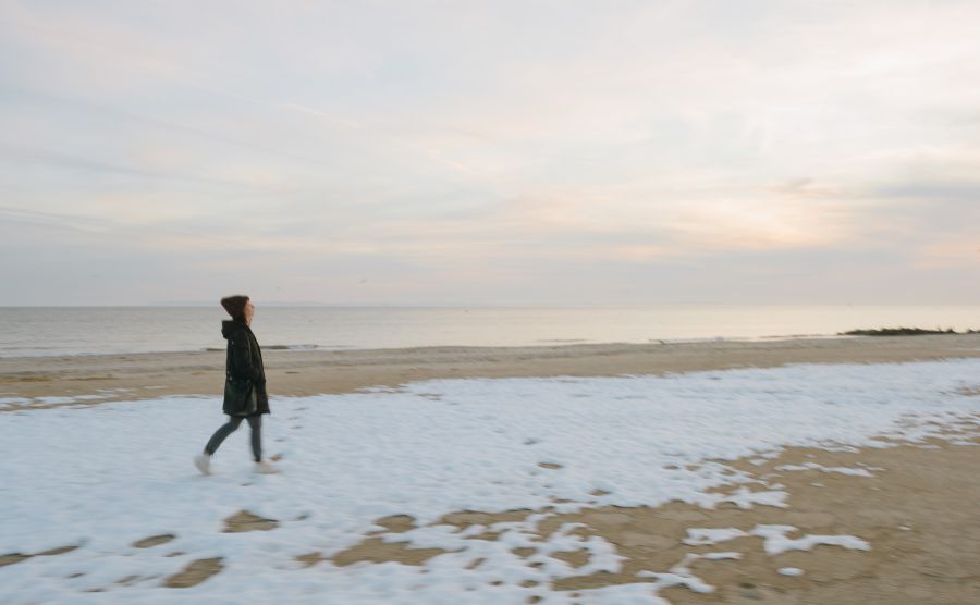 woman walking snow-covered coney island beach
