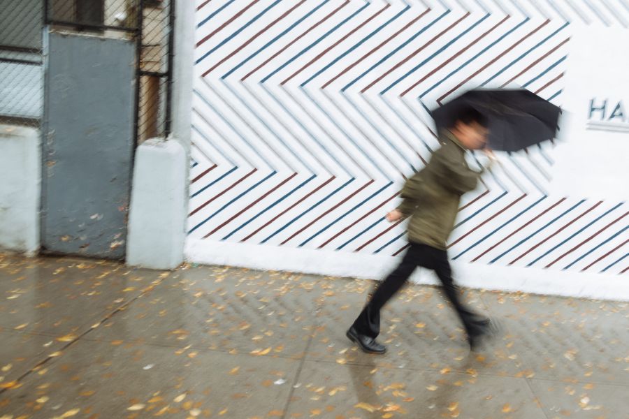 A man under an umbrella dashes past a barber shop Houston Street